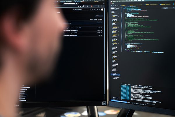 developer with his back to the code on the screens