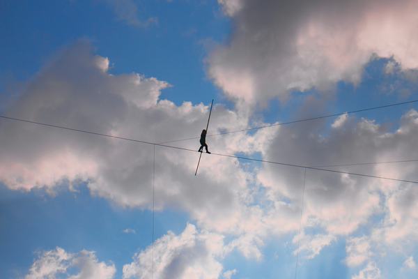 tightrope walker crossing between two buildings